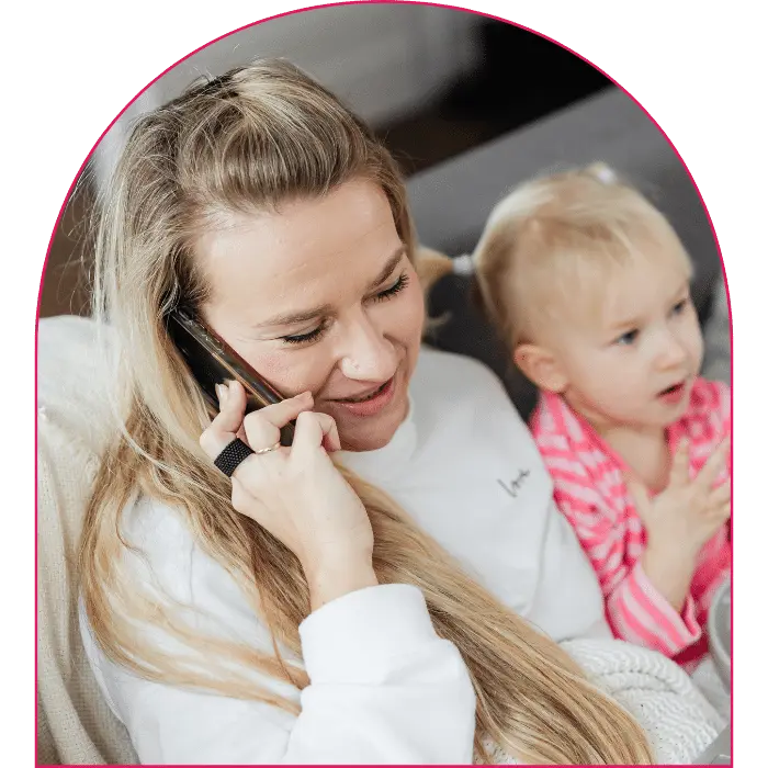 Woman making phone call on mobile phone while sitting on couch with baby